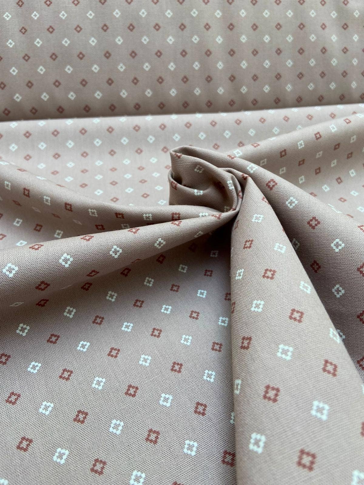 Close-up of fabric with a small geometric pattern on a beige background