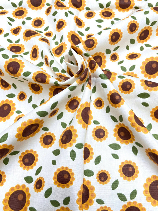 Sunflower pattern fabric with yellow flowers and green leaves on a white background
