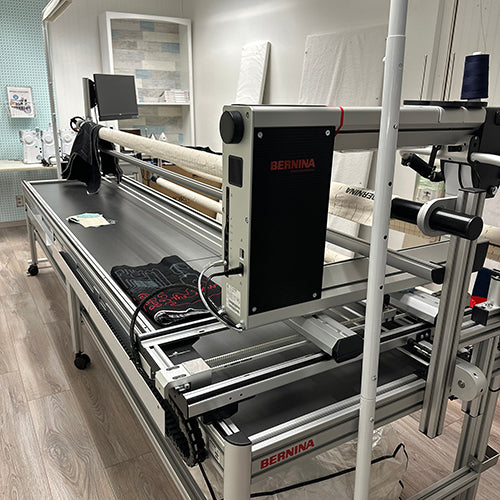 Large industrial sewing machine with 'Bernina' branding in a workshop setting.